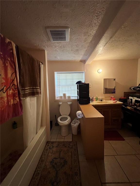 full bathroom featuring vanity, toilet, tile patterned floors, and a textured ceiling