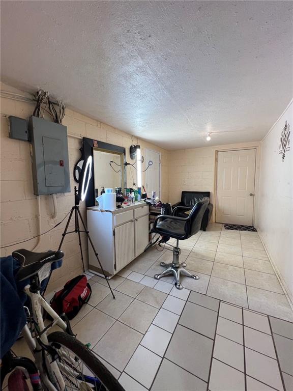 office area with electric panel, a textured ceiling, and light tile patterned floors