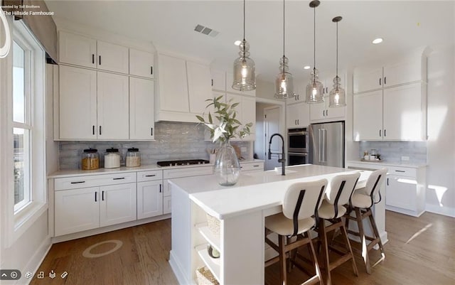 729 Keystone Dr, Woodstock, GA 30188 - kitchen with stainless steel appliances, tasteful backsplash, a center island with sink, light wood finished floors, and white cabinetry