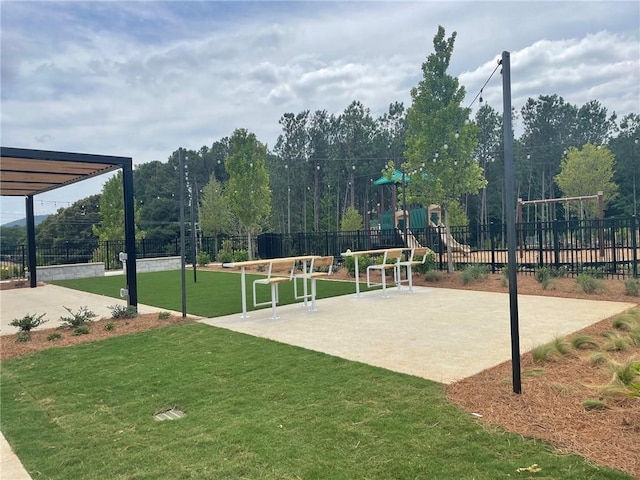 view of property's community featuring a lawn, playground community, and fence