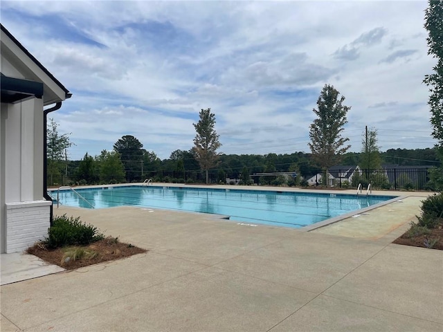 community pool with a patio area and fence