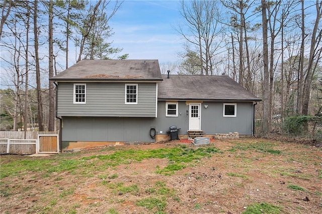 rear view of house featuring entry steps and fence