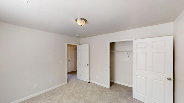 unfurnished bedroom with light carpet, baseboards, and a closet