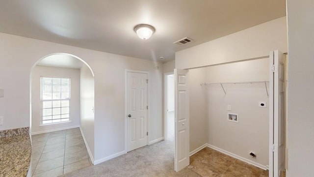 clothes washing area featuring hookup for an electric dryer, washer hookup, arched walkways, light tile patterned floors, and baseboards
