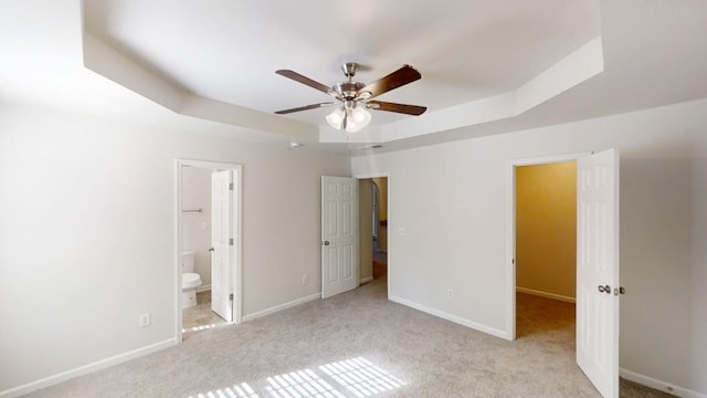 unfurnished bedroom with a tray ceiling, carpet flooring, and baseboards