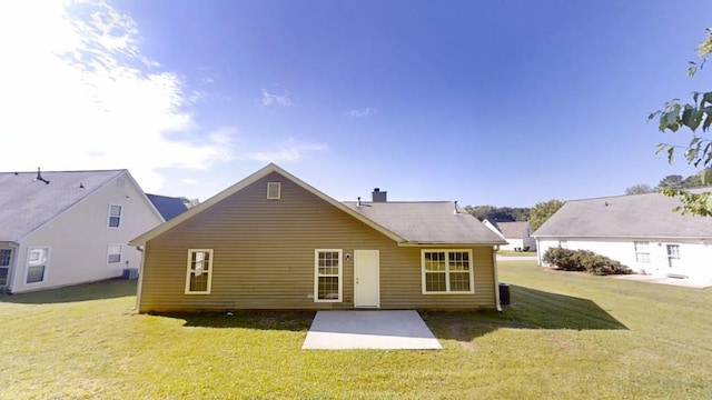 rear view of house featuring a patio area, a yard, and a chimney
