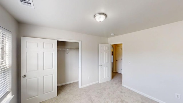 unfurnished bedroom featuring baseboards, light carpet, and a closet