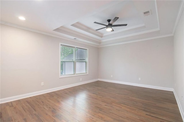 spare room with crown molding, a tray ceiling, dark hardwood / wood-style flooring, and ceiling fan