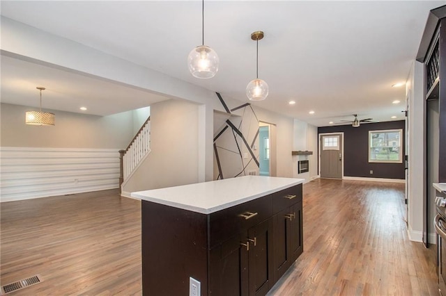 kitchen featuring decorative light fixtures, light hardwood / wood-style floors, a center island, and ceiling fan