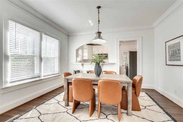 dining space featuring ornamental molding, baseboards, and wood finished floors