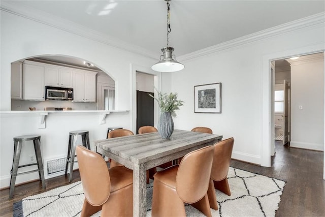 dining space featuring visible vents, crown molding, baseboards, and wood finished floors