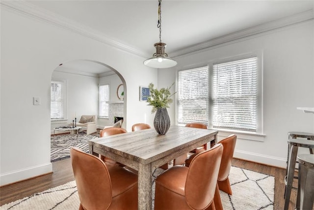 dining space with plenty of natural light, a fireplace, arched walkways, and wood finished floors