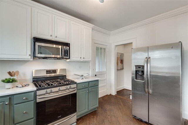 kitchen with dark wood finished floors, light countertops, green cabinets, appliances with stainless steel finishes, and ornamental molding