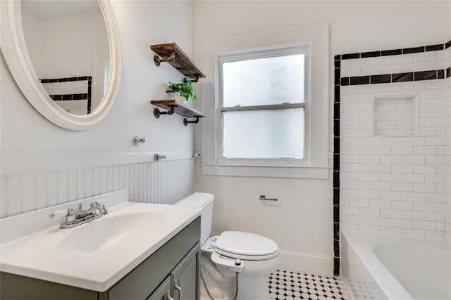 full bathroom with a wainscoted wall, vanity, toilet, and a healthy amount of sunlight