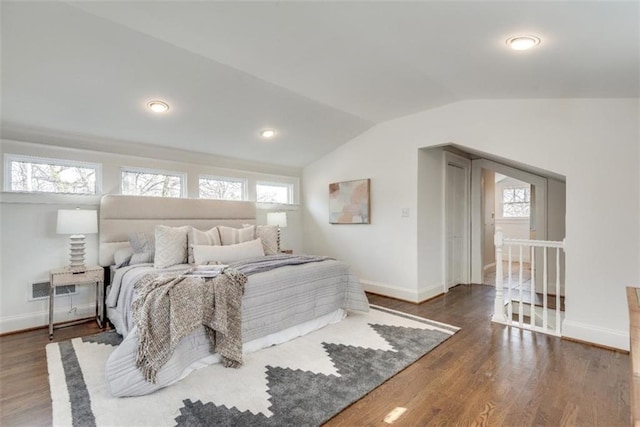 bedroom featuring lofted ceiling, visible vents, baseboards, and wood finished floors