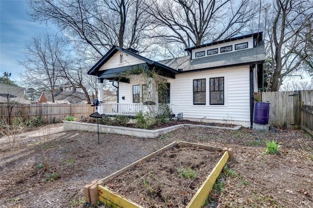 bungalow featuring covered porch, a garden, and fence