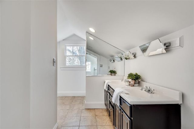 full bathroom featuring double vanity, baseboards, lofted ceiling, tile patterned floors, and a sink