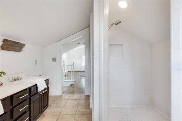 full bath with lofted ceiling, a tile shower, vanity, and tile patterned floors