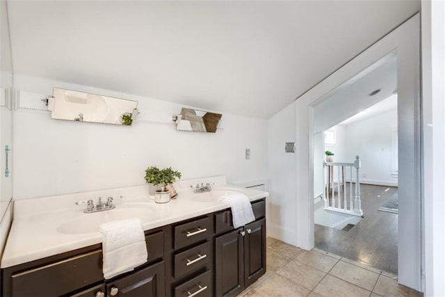 bathroom with vaulted ceiling, tile patterned flooring, vanity, and baseboards