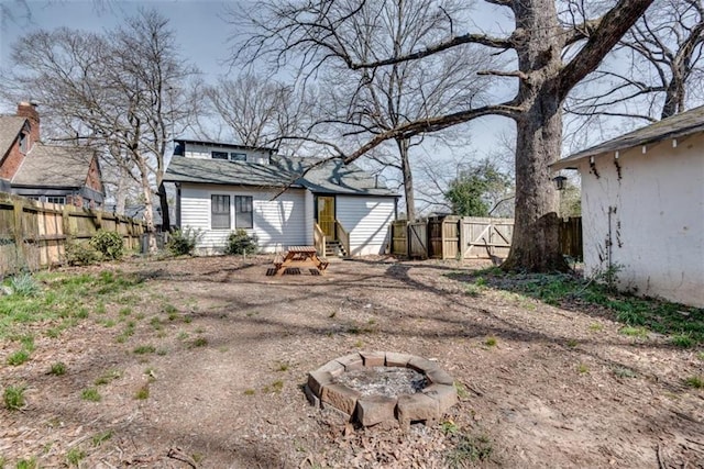 back of house featuring entry steps, an outdoor fire pit, fence, and a gate