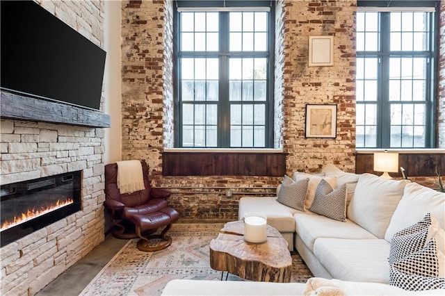 living area featuring plenty of natural light and a stone fireplace