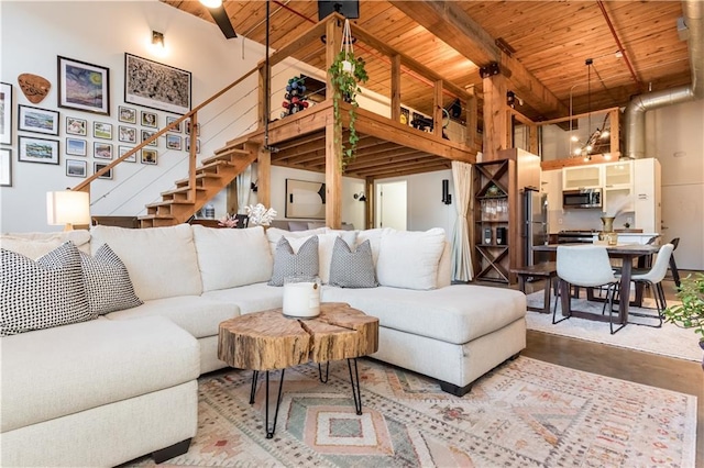 living room with a towering ceiling, wooden ceiling, stairway, and beam ceiling