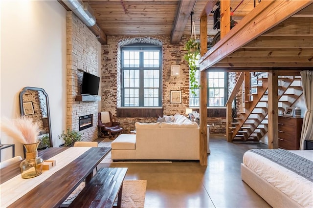 interior space with a fireplace, beam ceiling, concrete flooring, and multiple windows