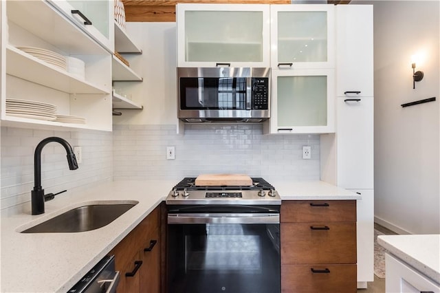 kitchen with stainless steel appliances, white cabinets, a sink, and glass insert cabinets