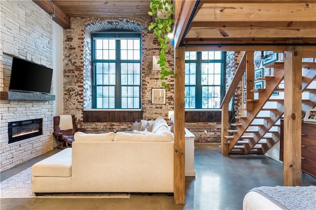 living room with finished concrete flooring, a stone fireplace, and stairs