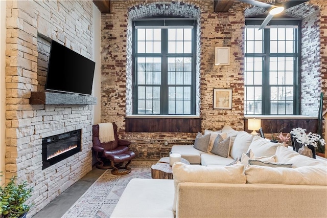 living area featuring concrete flooring, a stone fireplace, and a towering ceiling