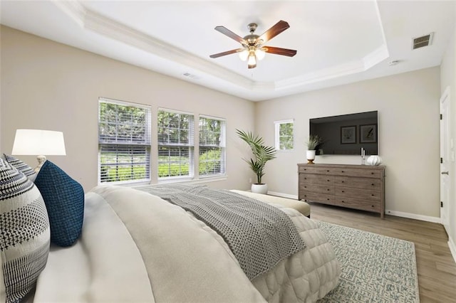7712 Soaring Eagle Dr, Flowery Branch, GA 30542 - bedroom with visible vents, crown molding, baseboards, light wood finished floors, and a tray ceiling