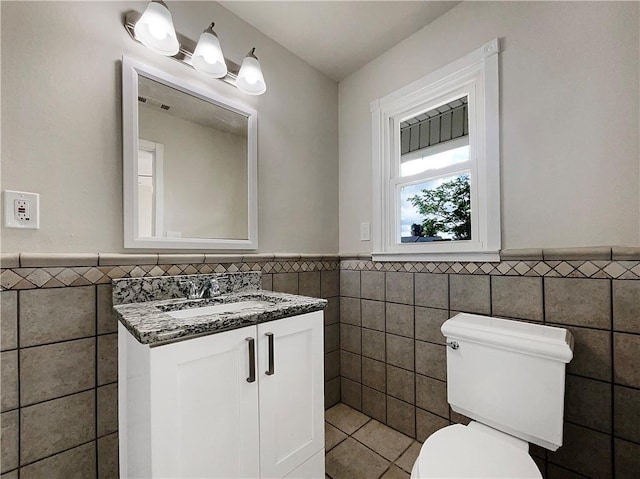 bathroom featuring vanity, tile walls, and toilet