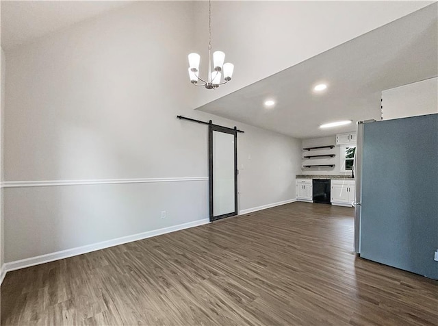 unfurnished living room featuring a barn door, dark wood-type flooring, and a chandelier