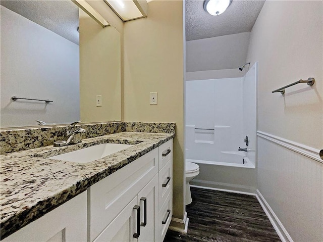 full bathroom with tub / shower combination, vanity, a textured ceiling, hardwood / wood-style flooring, and toilet