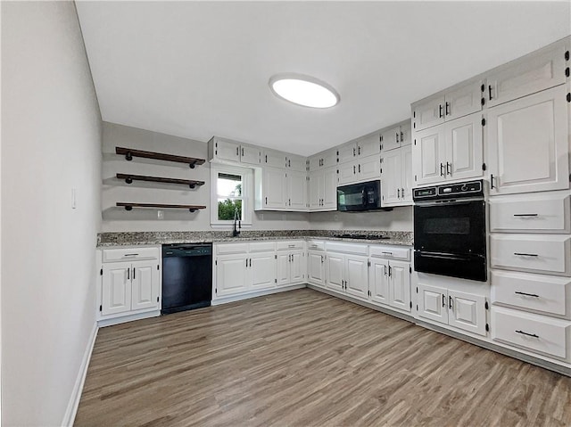 kitchen with white cabinets, black appliances, and light hardwood / wood-style floors