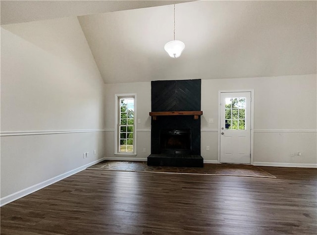 unfurnished living room with dark hardwood / wood-style floors, lofted ceiling, a fireplace, and a wealth of natural light