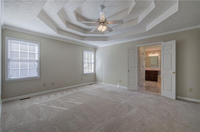 unfurnished bedroom with ceiling fan, a raised ceiling, crown molding, and multiple windows