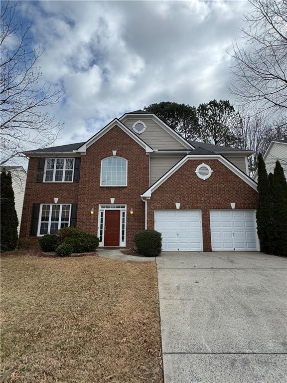 view of front of home featuring driveway, a front yard, a garage, and brick siding