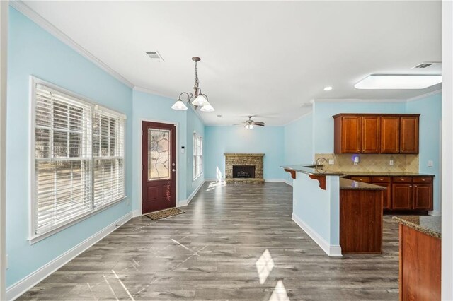 2143 Great Shoals Cir, Lawrenceville, GA 30045 - kitchen with a fireplace with raised hearth, open floor plan, decorative light fixtures, crown molding, and backsplash