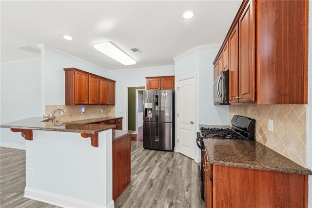 2143 Great Shoals Cir, Lawrenceville, GA 30045 - kitchen featuring visible vents, brown cabinetry, a kitchen breakfast bar, dark stone countertops, and stainless steel appliances