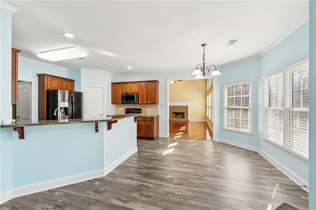 2143 Great Shoals Cir, Lawrenceville, GA 30045 - kitchen with stainless steel appliances, a kitchen breakfast bar, a wealth of natural light, brown cabinets, and decorative light fixtures