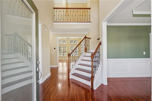 2143 Great Shoals Cir, Lawrenceville, GA 30045 - foyer featuring wainscoting, dark wood-style flooring, stairs, crown molding, and a decorative wall