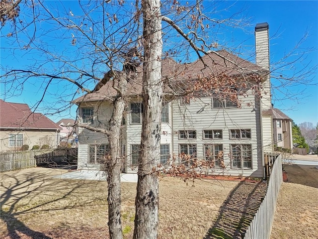 2143 Great Shoals Cir, Lawrenceville, GA 30045 - back of property featuring a fenced backyard, a patio, a chimney, and a lawn