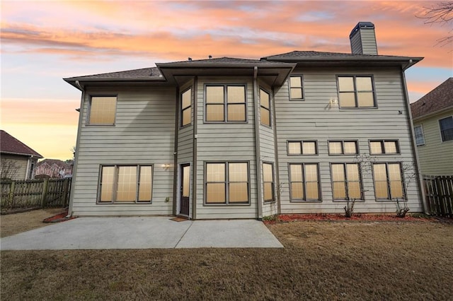 2143 Great Shoals Cir, Lawrenceville, GA 30045 - back of property at dusk featuring a chimney, a patio area, a yard, and a fenced backyard