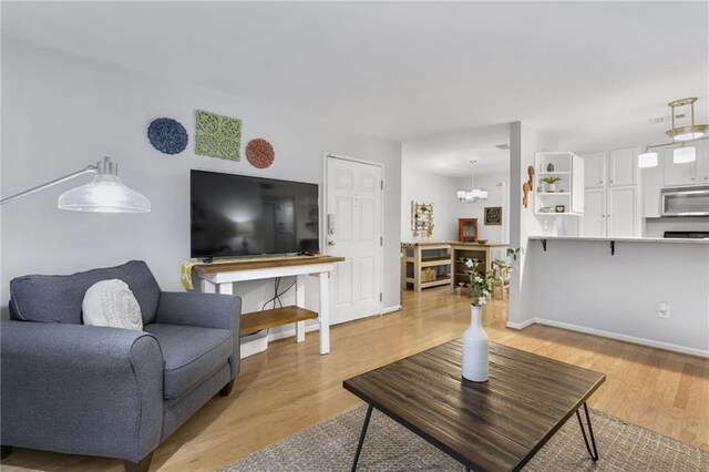 living room with an inviting chandelier and light wood-type flooring