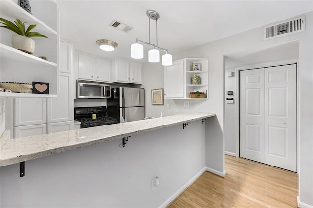 kitchen with decorative light fixtures, stainless steel appliances, a breakfast bar, and white cabinets