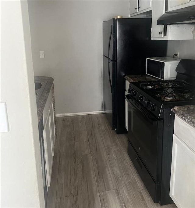 kitchen with dark hardwood / wood-style floors, dark stone countertops, black gas range, and white cabinetry