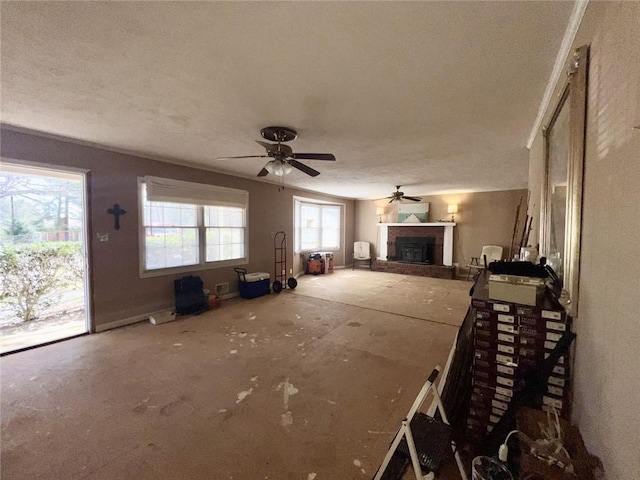 unfurnished living room with a fireplace with raised hearth, a textured ceiling, and ceiling fan