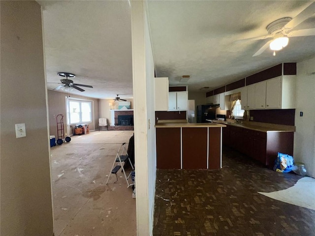 kitchen featuring a fireplace, white cabinets, a ceiling fan, and open floor plan