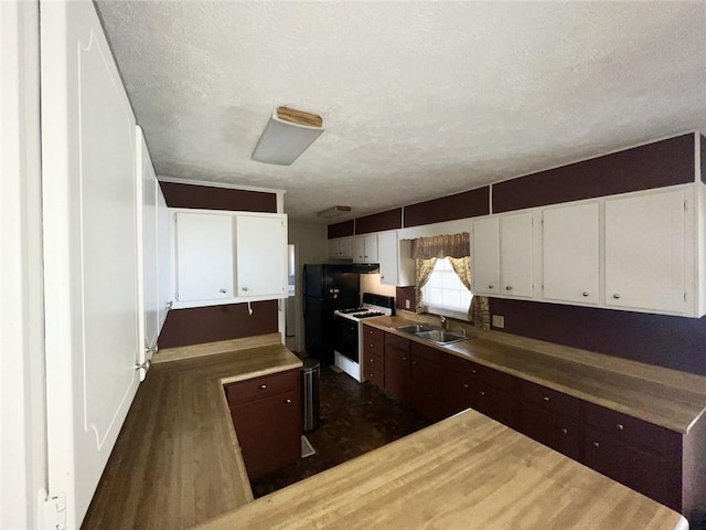 kitchen with white gas stove, dark wood finished floors, white cabinets, a textured ceiling, and a sink